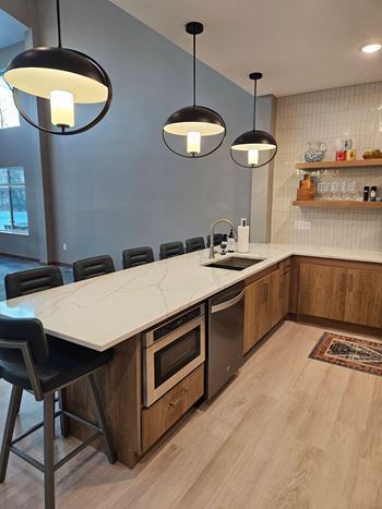 A modern kitchen with a long island and black chairs.